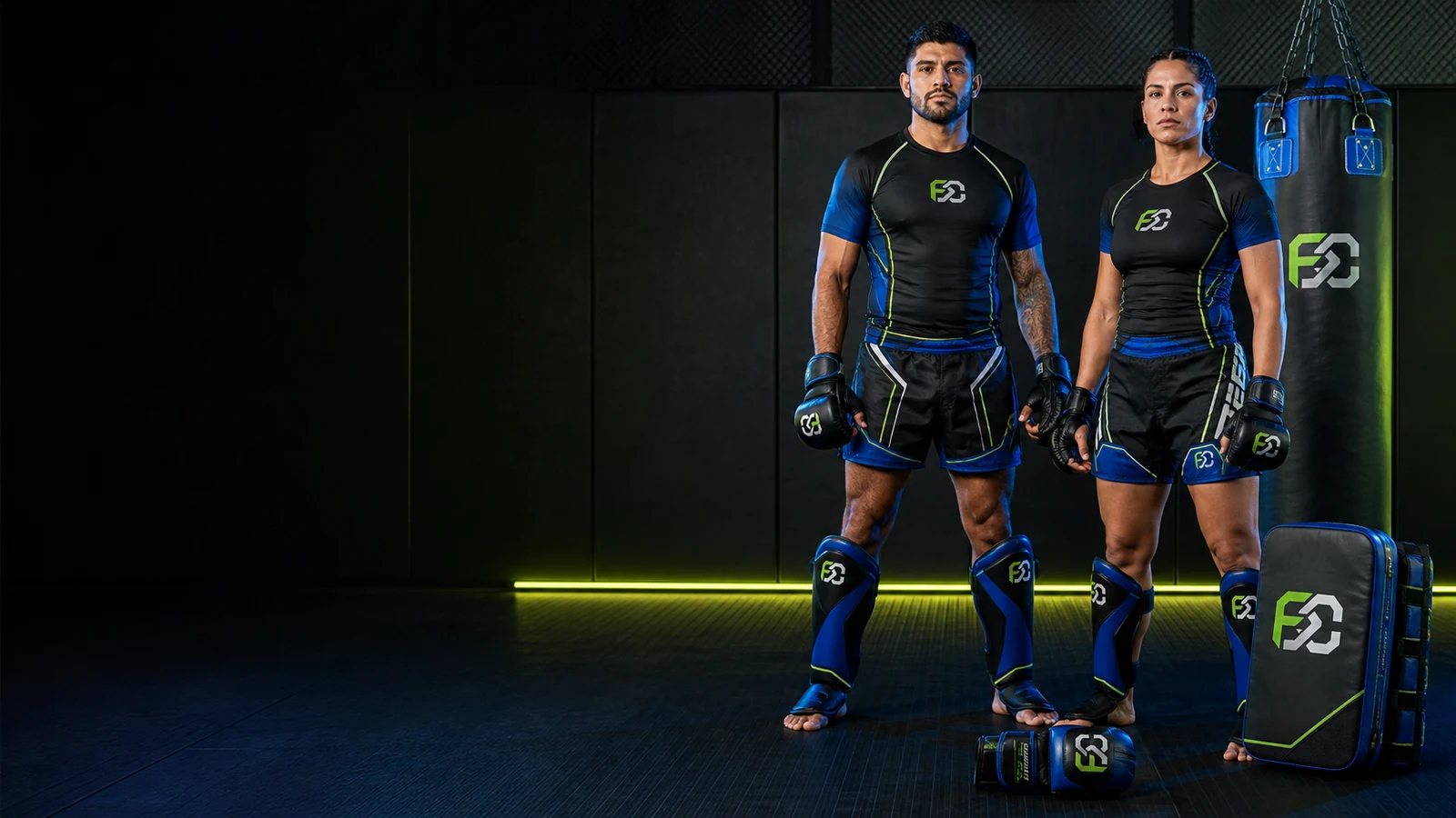 Two MMA athletes in shin guards and fight shorts beside kicking shields